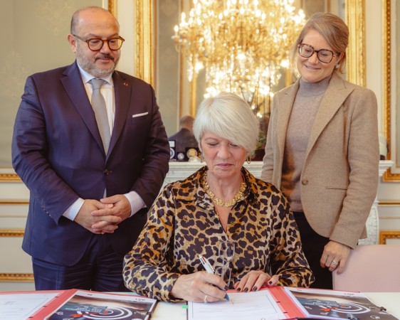 Photo de Laura Szabo signant le plan stratégique, accompagnée par les ministres Quintin et Van Bossuyt
